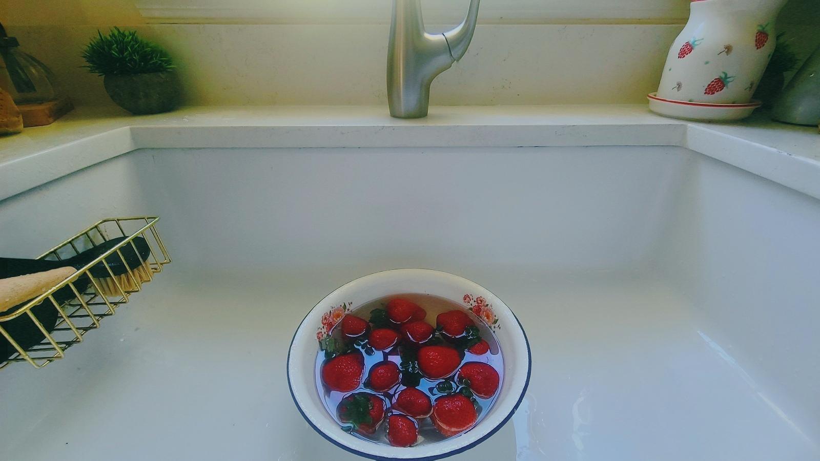 Fresh strawberries floating in a bowl in Moni's kitchen sink